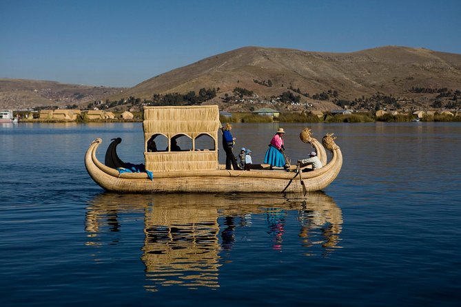 Caballito de totora navegando en el lago Titicaca junto a las islas flotantes de los Uros.